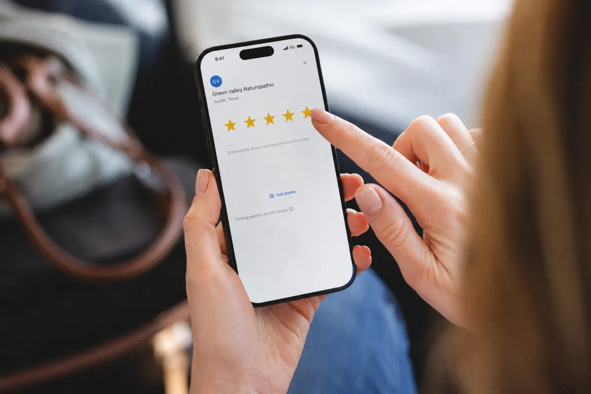 Patient leaving a five-star Google review for her naturopathic clinic on her phone